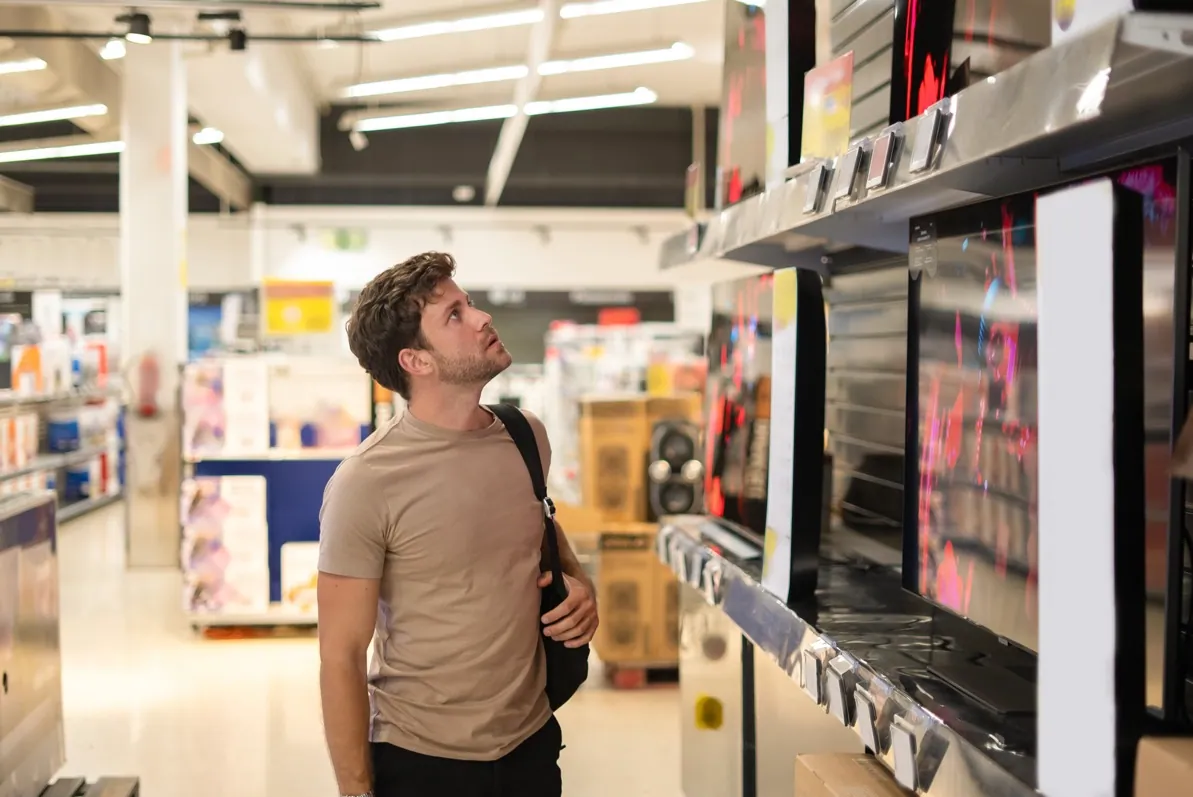 A customer comparing televisions in an electronics store
