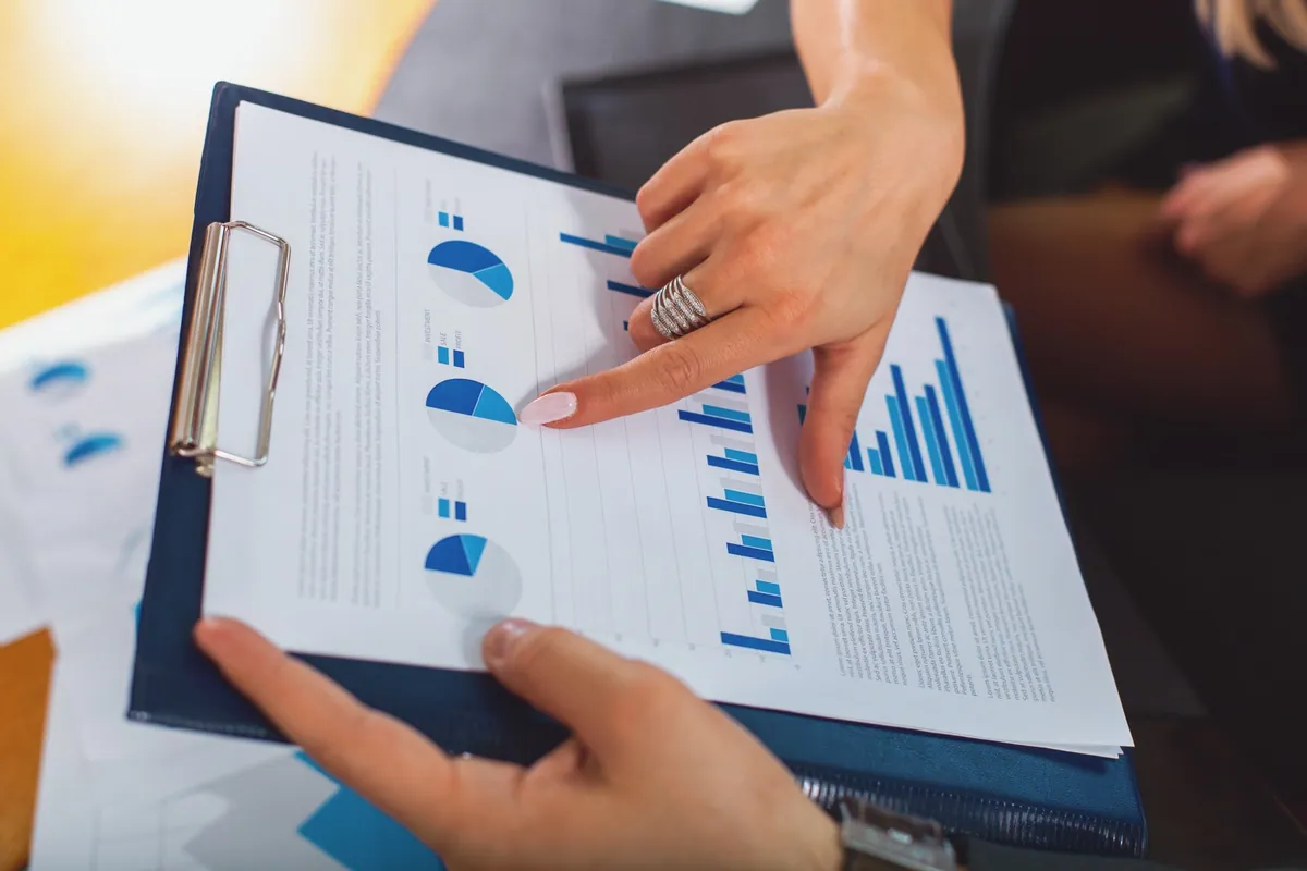 Two professionals reviewing printed business charts and performance reports