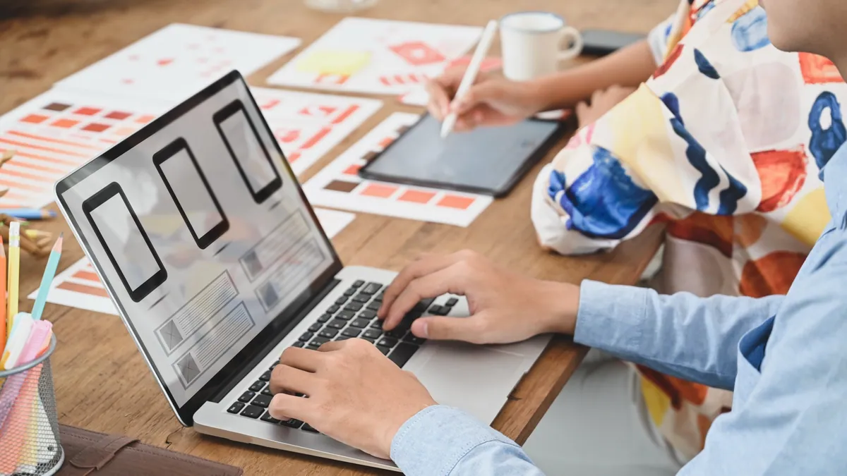 Designers arranging page layouts on a laptop and tablet