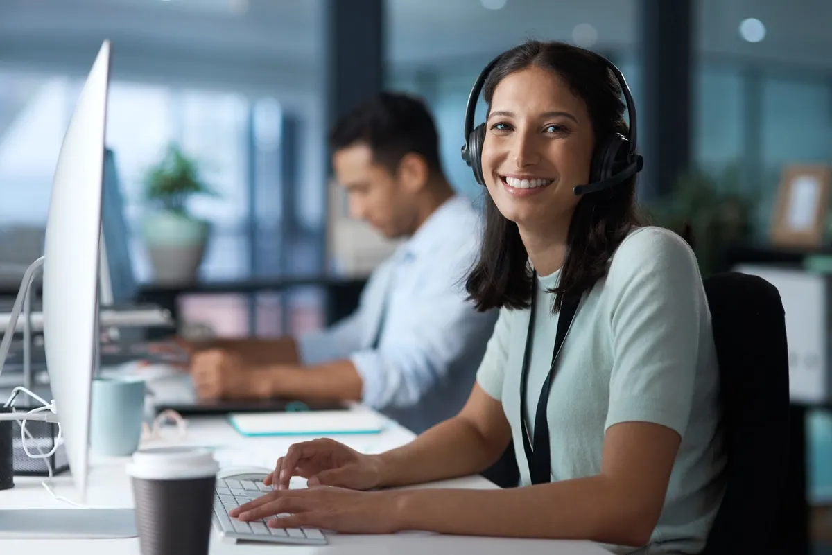 A support professional wearing a headset and working at a computer